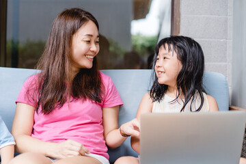 Happy asian mother and kid girl with laptop computer at home.teacher mother is teach her children during coronavirus covid19 lockdown.Education, Online learning, back to school.School kid.Homeschool.