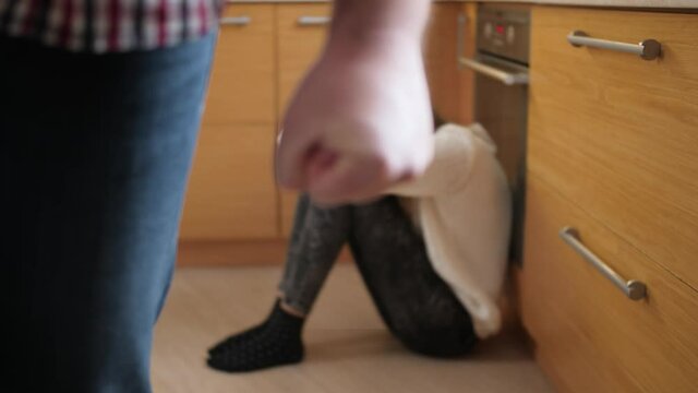 Angry man walking away from crying girl sitting on floor. Concept of domestic violence and family aggression.