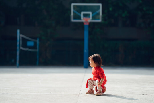 little baby girl playing basketball outdoors