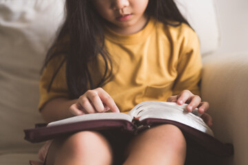 Asian kid girl read bible study.Worship at home.Sunday school.Bible on kid hands.Family christian...