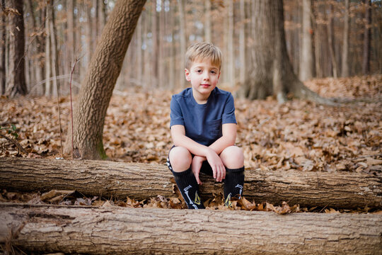 Young boy sitting on a log