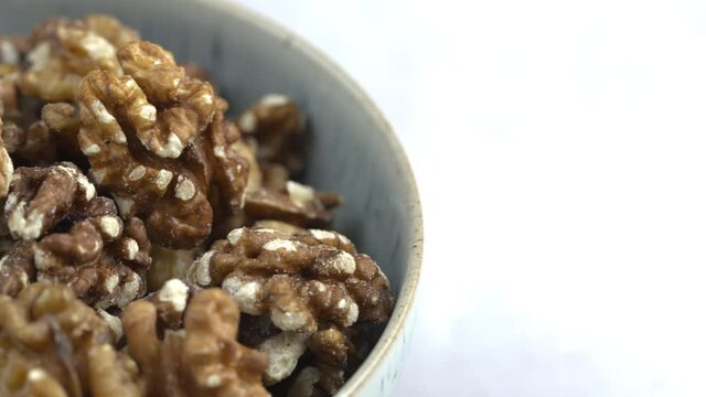 Pan Across A Bowl Of Walnuts.Nuts And Food On White Background. Protein Plant Based Raw Vegan Food. Health And Vegetarian Foods. Healthy Breakfast Ingredients. Macro 4K Shot.
