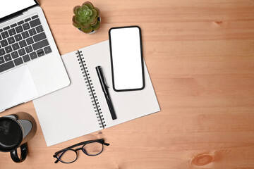 Top view mobile phone, laptop, notebook an glasses on wooden table.