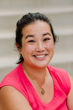 Headshot of smiling mid-30's asian woman wearing sleeveless pink top