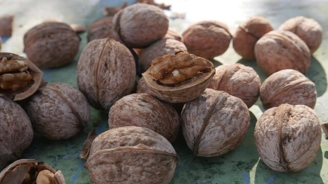 Walnut kernels and whole walnuts on rustic green old wooden table. Healthy snack food