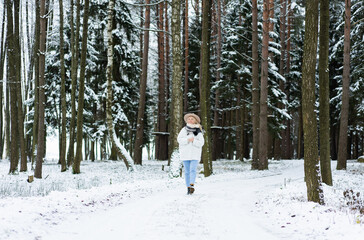 Woman walking along path in winter forest