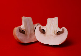 Fototapeta premium two mushrooms of mushrooms in a cut on a red background