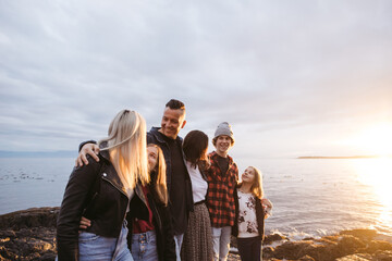 Candid family portrait on rocky beach at sunset.