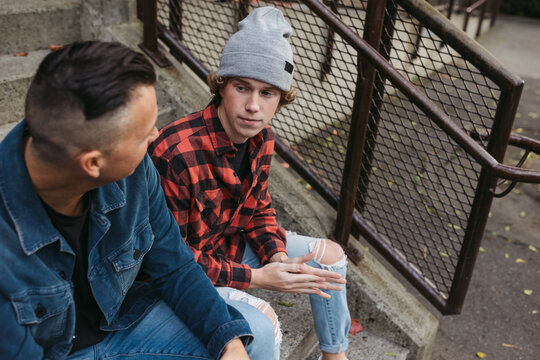 Father And Son Talking Together Outside On Steps In City Neighbo