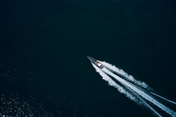Motor performance boat in the sea. Drone view of a boat sailing. Top view of a white boat sailing to the blue sea. Large white boat fast movement on blue water aerial view.