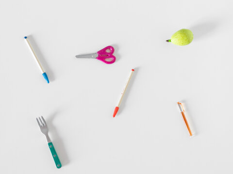 Minimalist still life with pear, pens, scissors and fork