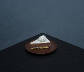 Miniature slice of chocolate and cream cake on a black table
