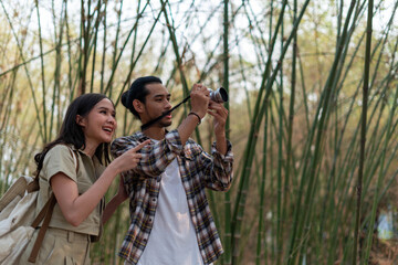 Male and female tourists are touring nature and taking pictures of the scenery. Couples go wild together on weekends. Nature tourism concept.