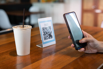 Men use phones to scan a qr code to select a menu or scan to receive a discount or pay for food and drink inside a cafe. using the phone to transfer money or pay online without cash concept.