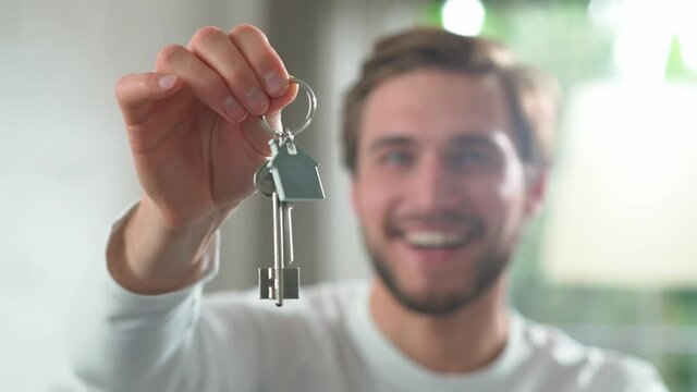 Housewarming, happy man in a new apartment, the male smiles and shows the keys to the new apartment to the camera, positive emotions, 4k slow motion.