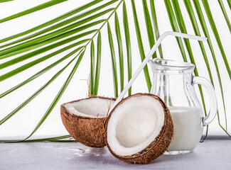 coconut with a white drinking tube and a jug of coconut milk