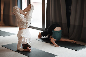 Unrecognizable man and woman doing yoga in studio