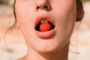 Sensual woman's mouth with raspberry