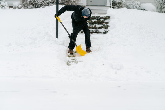 teenage boy shovelling his neighbour's pathway