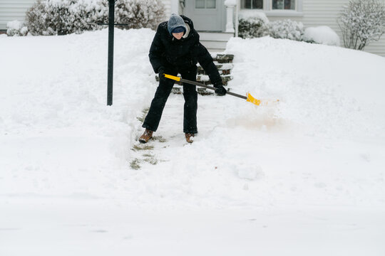 teenage boy shovelling his neighbour's pathway
