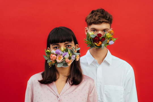 young couple in flower masks on a red background