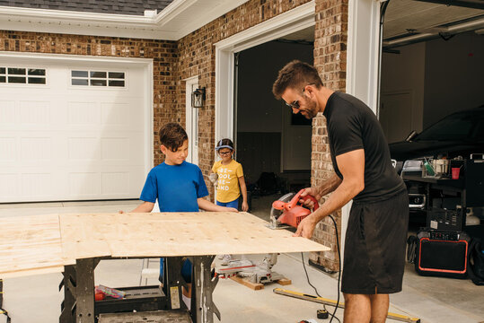 Dad working on a woodworking project with the help of his kids. 