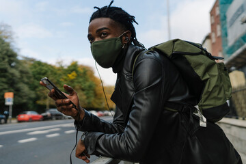 Man With Face Mask, Mobile Phone and Earbuds 