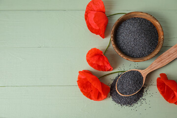 Bowl and spoon with poppy seeds and flower on color wooden background