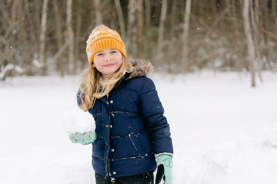 young girl holding a very big snowball 