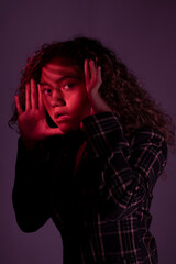 vertical portrait of a young latin woman posing with red ligth and dark background