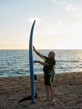 Aged man with windsurf table at the beach