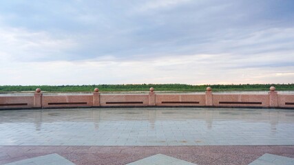 gray blue sky clouds rain clouds marble granite embankment wet after rain in the distance green forest