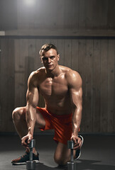 Fototapeta na wymiar Portrait of strong muscular bodybuilder doing exercises with dumbbells in gym