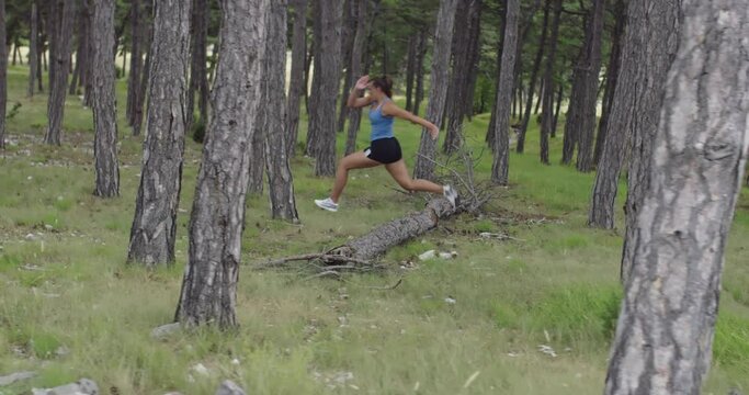 Female athlete running through the forest. An active young woman having an intense workout.
