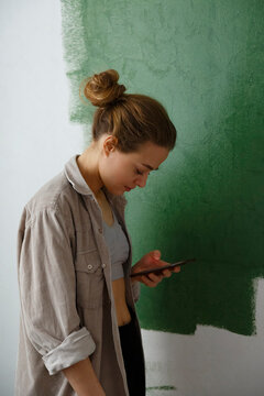Young female painter using mobile phone