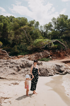 mother with toddler in swimwear looking over the ocean