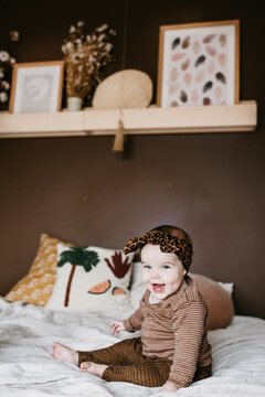 Little girl sitting on bed of parents and looking excited 