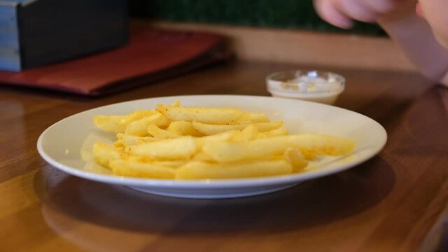 Little girl sitting at the table and eating French fries in cafe, Very shallow focus