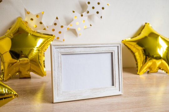 Portrait White Picture Frame Mockup On Wooden Table. Gold Baloons, Birstday Concept. White Wall Background. Scandinavian Interior. Vertical.	