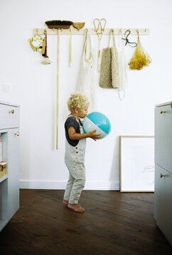 Toddler boy with inflatable bal walking through the kitchen