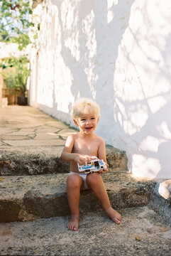 Little boy playing with plastic car outside