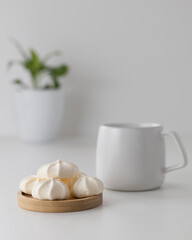 cream meringues in a wooden plate with cup on a white background 