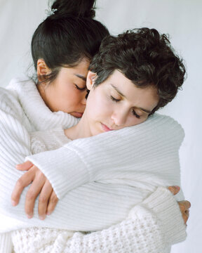 Hugs of two pretty girls in white sweaters 