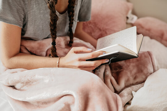 young woman reading her notebook in her bedroom
