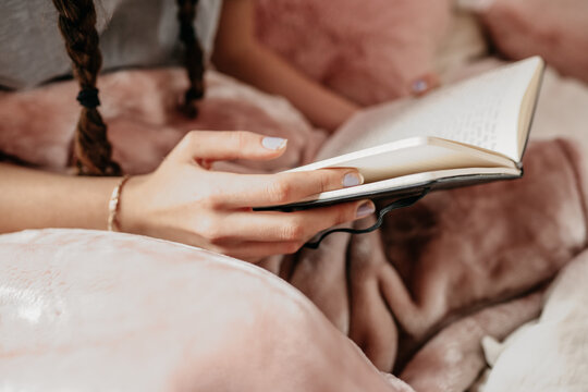 young woman reading her notebook in her bedroom