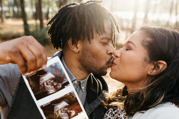 A man and woman holding up an ultrasound of their child and kissing - pregnancy announcement 