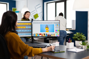 Professional photographer sitting at desk putting on headphones for listening music using PC in photo studio retouches. Content creator doing portrait retouching using post production software