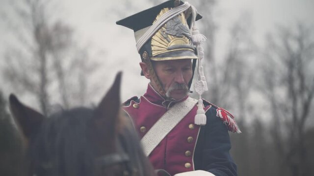 Portrait of a adult male hussar in medieval costume, soldier on horseback, talks to a fellow soldier on the battlefield, the battle of Napoleon, close-up.