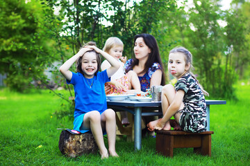 A young large family at a picnic on a summer morning.Mother with children is having breakfast in...