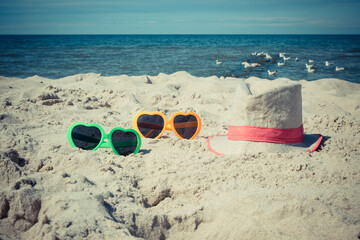 Sunglasses and straw hat on sand at beach. Sun protection while sunbathing. Travel and vacation time